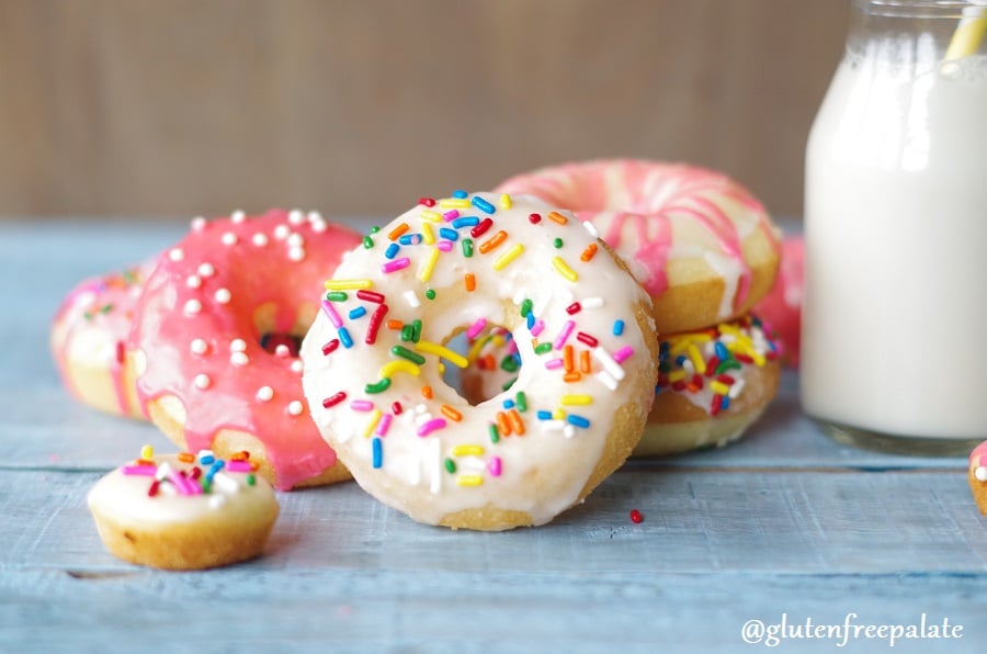 Vanilla Birthday Cake Donuts on a blue board with a glass of milk.