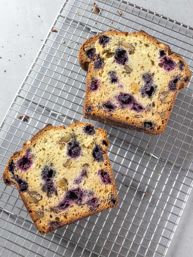 Two slices of lemon blueberry bread on a cooling rack.