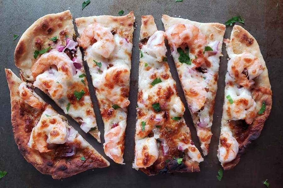 Sliced shrimp scampi pizza on metal baking sheet