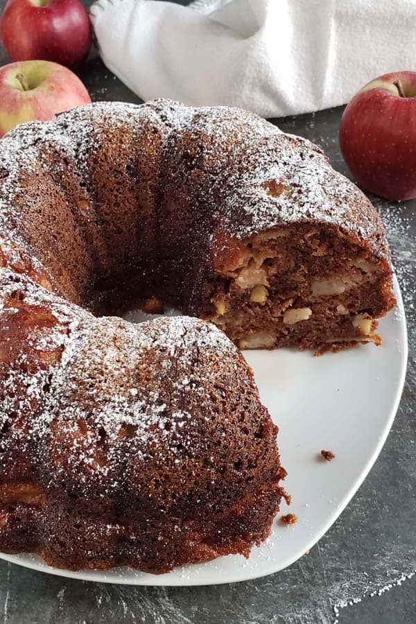 Apple cake baked in a bundt pan on a white plate.