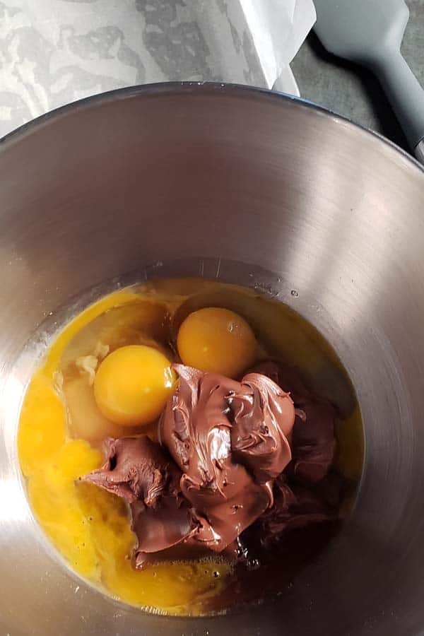 Nutella, eggs, and melted butter in a metal bowl.
